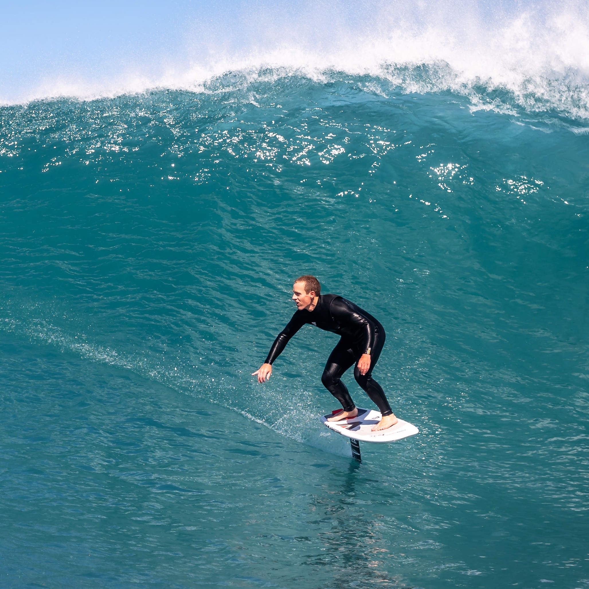 Surfeur en foil Armstrong Performance Mast sur grande vague et mer bleu clair
